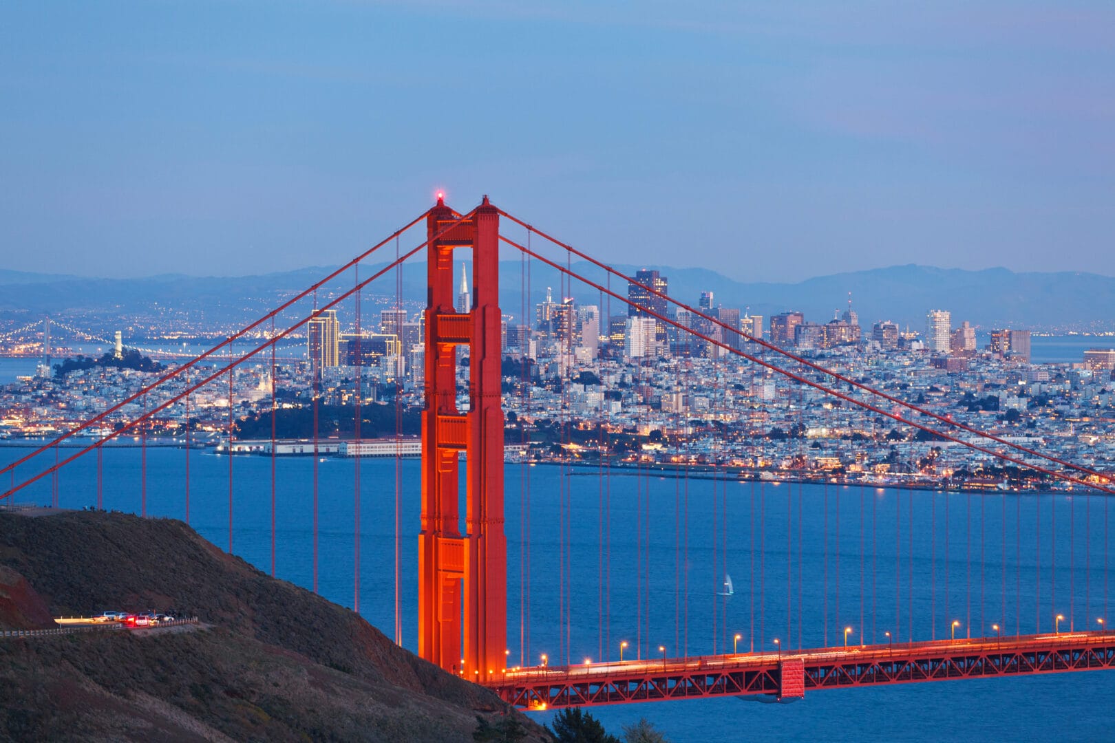 Illuminated Golden Gate Bridge and San Francisco Skyline at dusk.